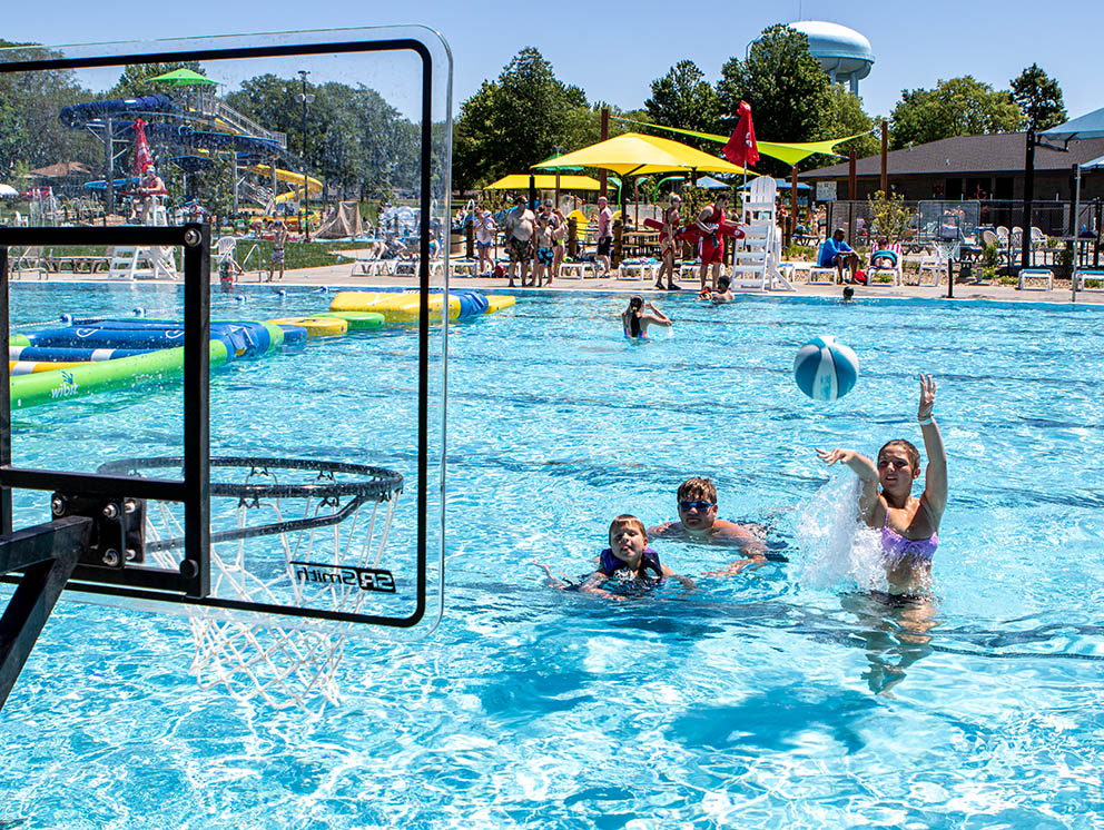 Family shooting hoops in pool.